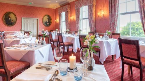 奥尔德堡温特沃斯酒店的一间设有白色桌椅和窗户的用餐室