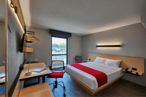 墨西哥城City Express Plus by Marriott Periferico Sur Tlalpan的一间卧室配有一张床、一张书桌和一个窗户。