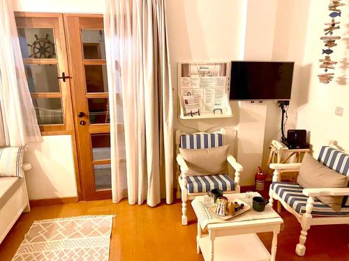 KoríthionCoralina Cottage的客厅配有两把椅子和电视