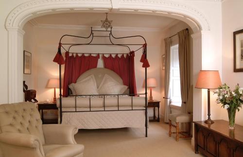 科姆里皇家酒店的一间卧室配有一张带红色窗帘的天蓬床