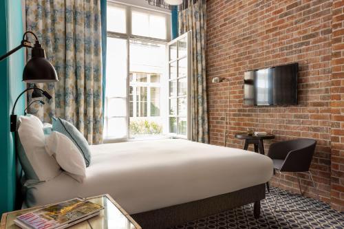 巴黎法布里克酒店的一间卧室设有一张床和砖墙