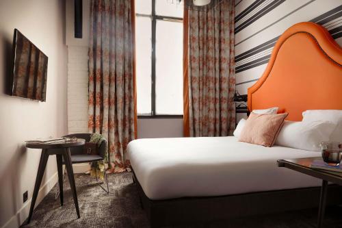 巴黎法布里克酒店的酒店客房,配有带橙色床头板的床