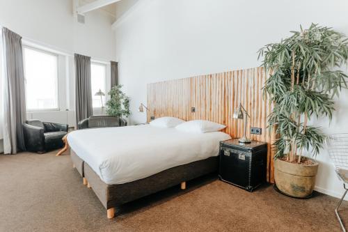 埃因霍温女王酒店的一间卧室配有一张大床和两株盆栽植物