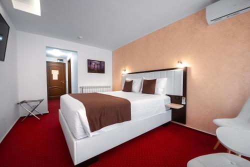旧瓦马Km ZerO - Vama Veche的酒店客房配有一张大床和红地毯。
