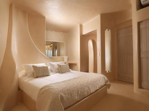 易莫洛林Dome Santorini Resort & Spa的卧室配有一张带白色床单和枕头的大床。