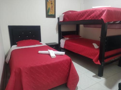 麦德林HOGAR DEL VIAJERO的一间卧室配有两张双层床,铺有红色床单