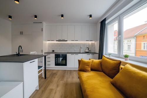 瓦尔米亚地区利兹巴克Apartament Alpaka 2的一间带黄色沙发的客厅和一间厨房