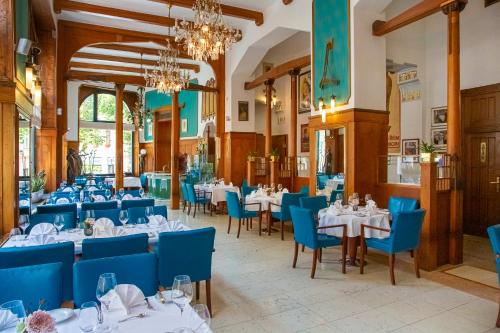 布拉格布拉格巴黎酒店的餐厅设有白色的桌子和蓝色的椅子