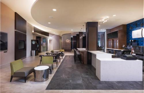 格林维尔Courtyard by Marriott Greenville Downtown的大堂设有酒吧和桌椅