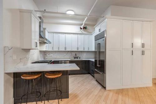 纽约Luxurious 2 Bedroom Loft Entire Apartment的一间厨房,配有白色橱柜和一个带酒吧凳的厨房岛
