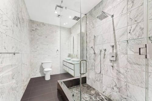 纽约Furnished and Meticulously Renovated 3-bedroom, 2-bathroom Loft的带淋浴、卫生间和盥洗盆的浴室