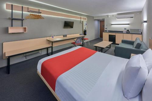 CananeaCity Express by Marriott Cananea的酒店客房配有一张床、一张书桌和一张沙发。