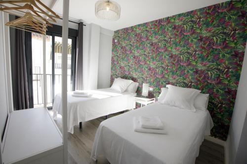 科尔多瓦Atico Casa Lola的一张带花卉壁纸的客房内的两张床