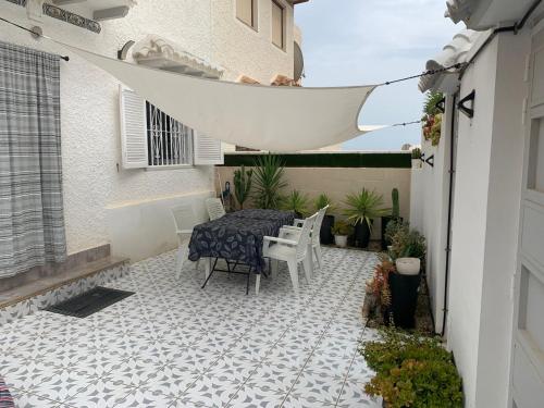 托雷维耶哈Casa de la playa的铺有瓷砖地板,设有带桌椅的庭院。