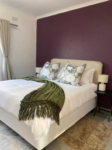 乌姆塔塔Urban & Comfortable Loft apartment in Mthatha的卧室配有白色床和紫色墙壁