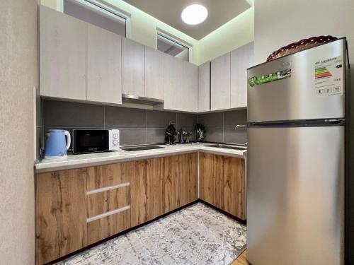 杜尚别Dushanbe City View Apartment的带木柜的厨房内的不锈钢冰箱