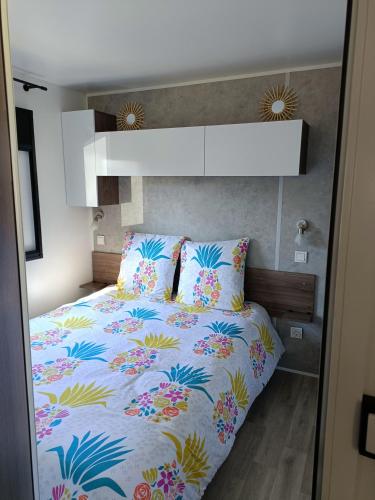 雷日卡普费雷mobil-home neuf 4-6 places camping Siblu les viviers的一间卧室配有一张带五颜六色棉被的床
