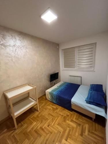 VoždivacAPARTMAN VOJVODA JJ的一间卧室配有一张带蓝色床单的床和电视。