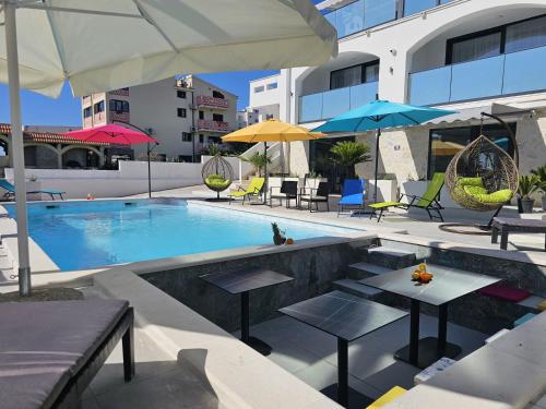 诺瓦利娅The Luxury Apartments - Villa Havana的大楼内带桌子和遮阳伞的游泳池