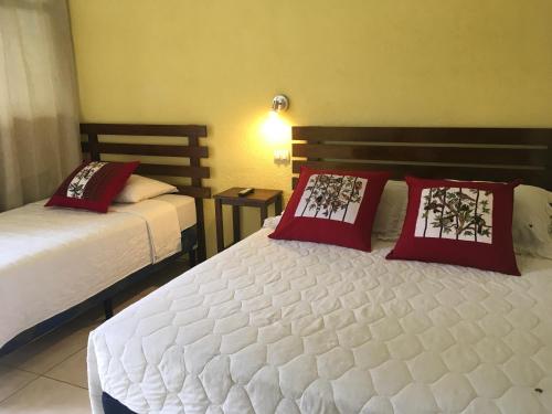 圣地亚哥阿蒂特兰Casa Josefa Hotel的一间卧室配有两张带红色枕头的床