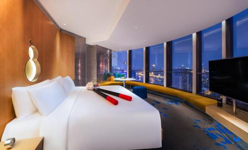 上海上海外滩W酒店的一间酒店客房,配有白色的床和一台平面电视