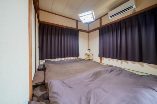 东京R-house 4th的一间卧室配有一张大床和紫色窗帘