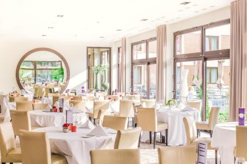 卢森堡阿尔维斯帕克酒店的餐厅配有白色的桌椅和镜子