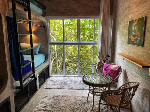 涛岛Wonderland Jungle Hostel的客房设有桌椅和窗户。