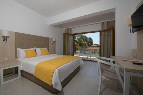 欧拉努波利斯Aristoteles Holiday Hotel And Spa的一间卧室配有一张床、一张书桌和一个窗户。