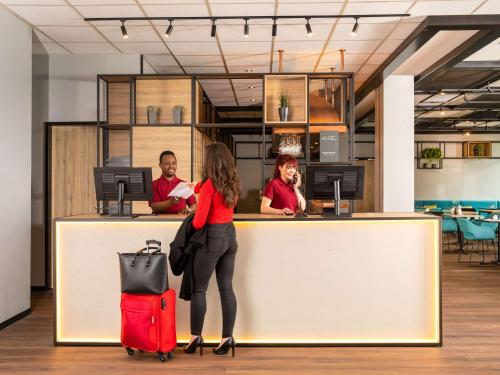多特蒙德多特蒙德市宜必思酒店的一位穿着红色手提箱站在柜台上的女人
