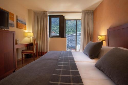 安道尔城Hotel Màgic Andorra的一间设有大床和窗户的酒店客房