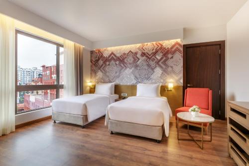 加德满都Dusit Princess Kathmandu的酒店客房,设有两张床和一张红色椅子