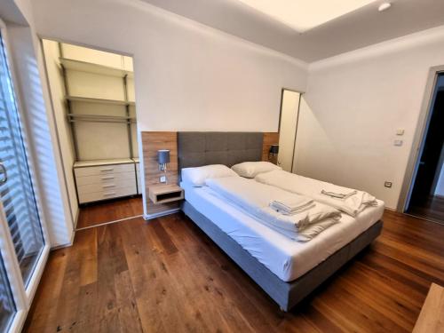林茨Mountains and Lakes - Villa Gaumberg的卧室配有一张白色的大床,铺有木地板