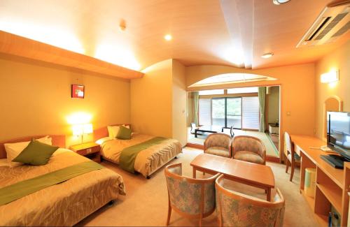 Komaba湯元ホテル阿智川的酒店客房设有两张床、一张桌子和一台电视。