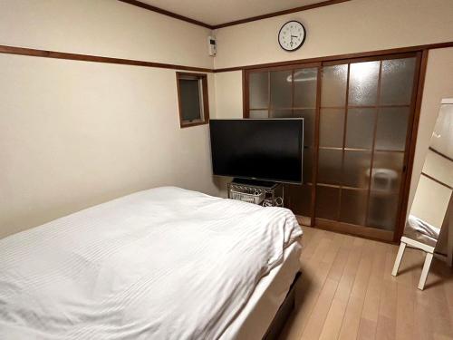广岛Casa Viento Stay Inn的一间卧室配有一张床和一台平面电视
