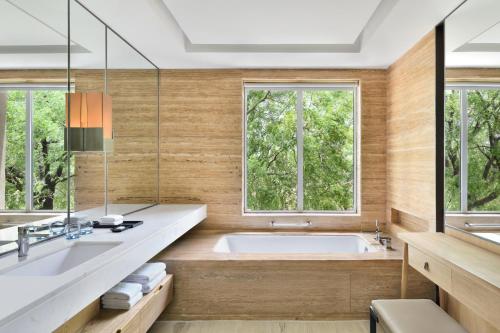 法里达巴德Courtyard by Marriott Aravali Resort的带浴缸的浴室和2扇窗户
