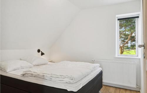 班霍尔姆Awesome Home In Bandholm With House Sea View的一间卧室配有一张带白色床单的床和一扇窗户。