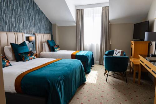 拉辛赫Lahinch Coast Hotel and Suites的酒店客房配有两张床和一张书桌