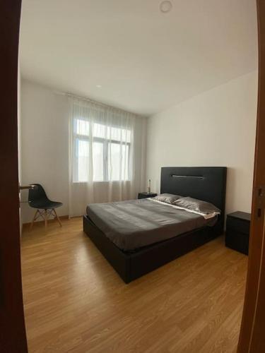 布拉加Apartamento em braga的卧室铺有木地板,配有一张床和一把椅子