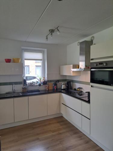阿姆斯特丹Dubbelink 3A的一间设有白色橱柜和窗户的大厨房