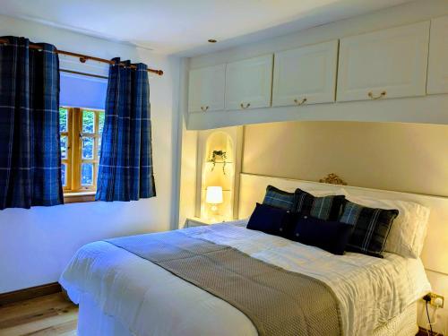 卢斯Heather Cottage Luss的一间卧室配有一张带蓝色窗帘的大床