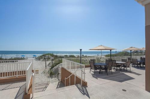 杰克逊维尔海滩杰克逊维尔海滩海滨万怡酒店的海滩上带桌椅和遮阳伞的天井