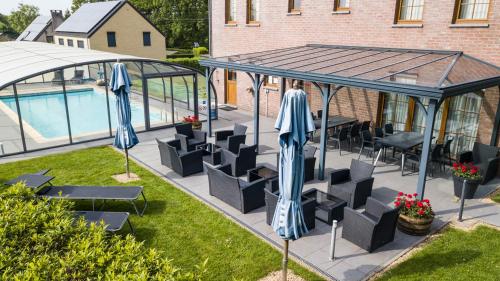 特镇Logis Hôtel Le Menobu的游泳池旁带椅子和遮阳伞的天井