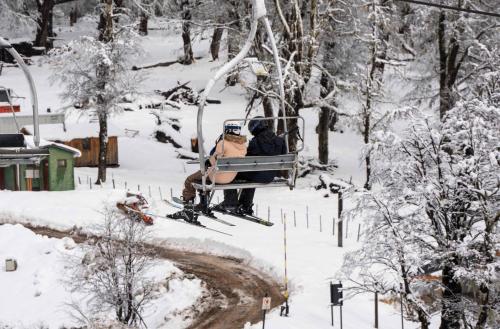 圣马丁德洛斯El Refugio Ski & Summer Lodge的两个人坐在雪地里的滑雪缆车上
