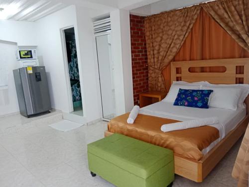 图马科HOTEL SAN MARINO TUMACO的一间卧室配有一张大床和一个绿色的搁脚凳