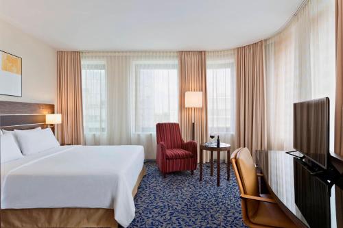 维也纳维也纳普拉特公园/博览会万怡酒店的酒店客房带白色的床和红色椅子