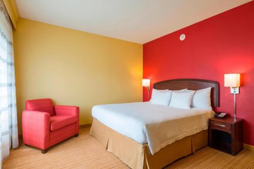 威尔明顿威尔明顿布兰迪万怡酒店的一间卧室设有一张床和红色的墙壁