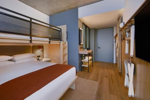 悉尼Moxy Sydney Airport的酒店客房带一张床铺、一张书桌和一间卧室