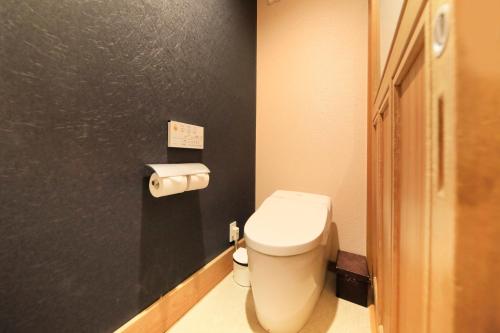 富士河口湖富士温泉寺梦殿日式旅馆的浴室设有白色卫生间和黑色墙壁。