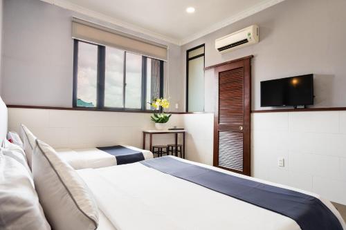 胡志明市Văn Hoa Hotel的酒店客房设有两张床和一台平面电视。